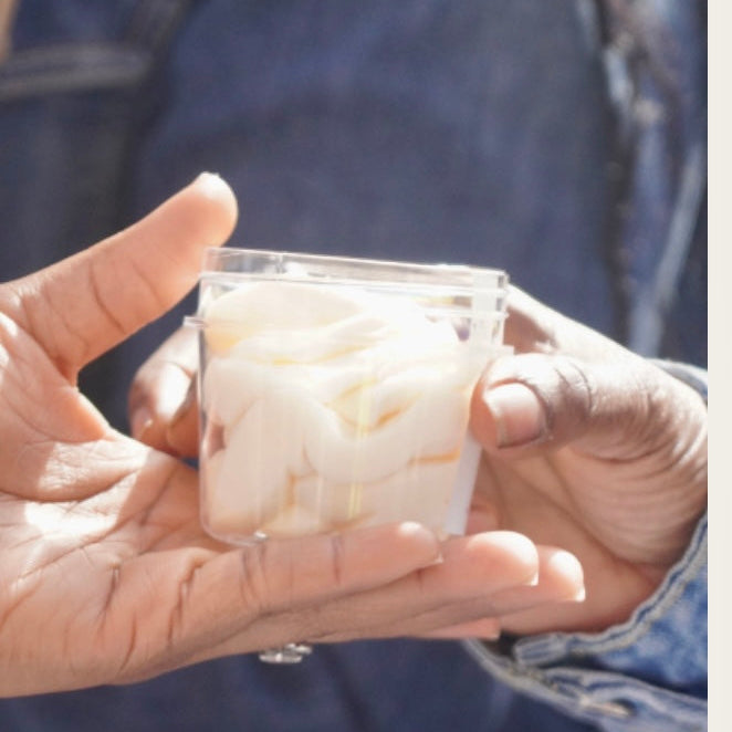 Person holding a clear container with food against a blurred denim background
